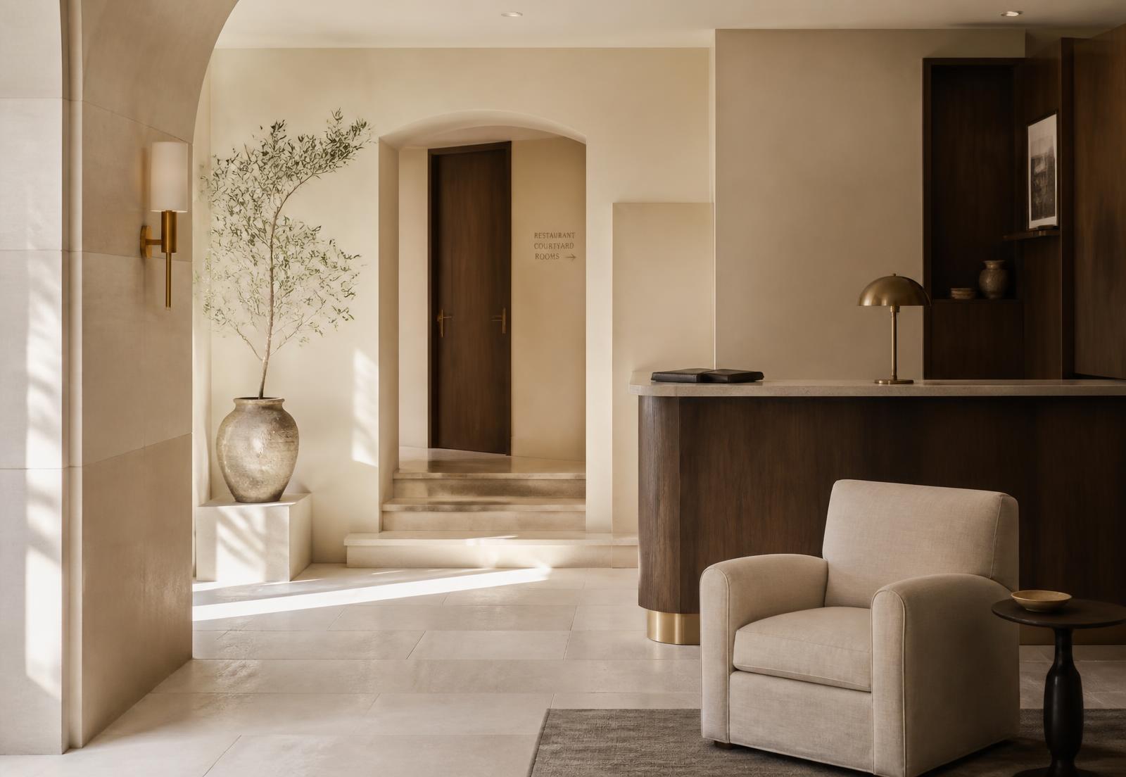 Calm hotel lobby with warm neutral finishes and brass detailing
